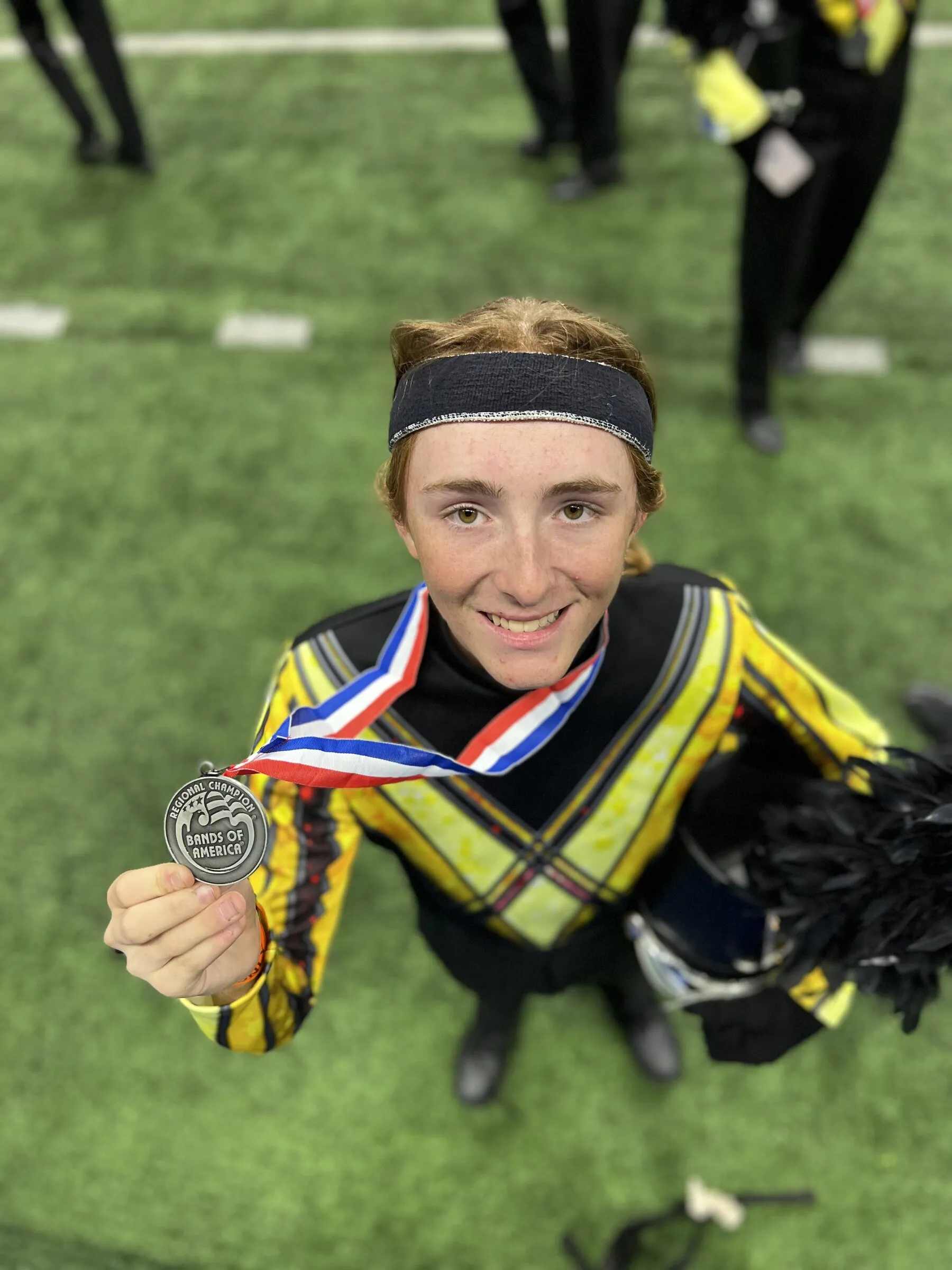 Jonas smiling in his marching band uniform, holding up a medal